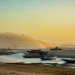 Barcos diante de dunas na praia de Jericoacoara ao pôr do sol