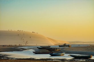 Barcos diante de dunas na praia de Jericoacoara ao pôr do sol