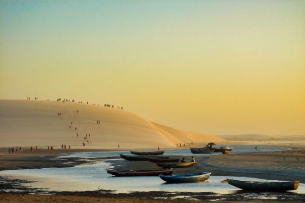 Barcos diante de dunas na praia de Jericoacoara ao pôr do sol