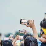 Pessoas reunidas em uma praça usando smartphones durante um evento