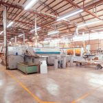 Interior de uma fábrica industrial organizada, com máquinas e equipamentos de produção.
