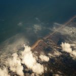 Vista aérea do litoral com áreas de nuvens cobrindo o oceano e a faixa de terra.
