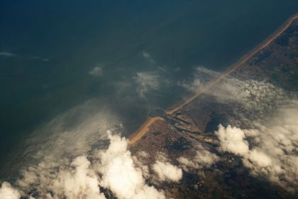 Vista aérea do litoral com áreas de nuvens cobrindo o oceano e a faixa de terra.