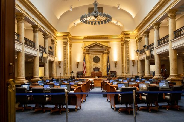 Interior de um plenário legislativo amplo, com colunas, assentos e espaço destinado às atividades parlamentares.