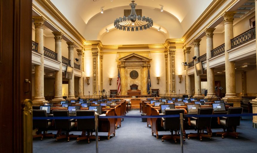 Interior de um plenário legislativo amplo, com colunas, assentos e espaço destinado às atividades parlamentares.