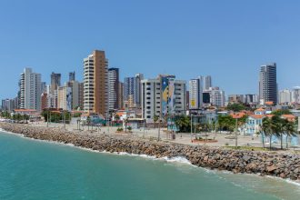 Vista da orla de Fortaleza, no Ceará, com edifícios altos junto à faixa costeira.